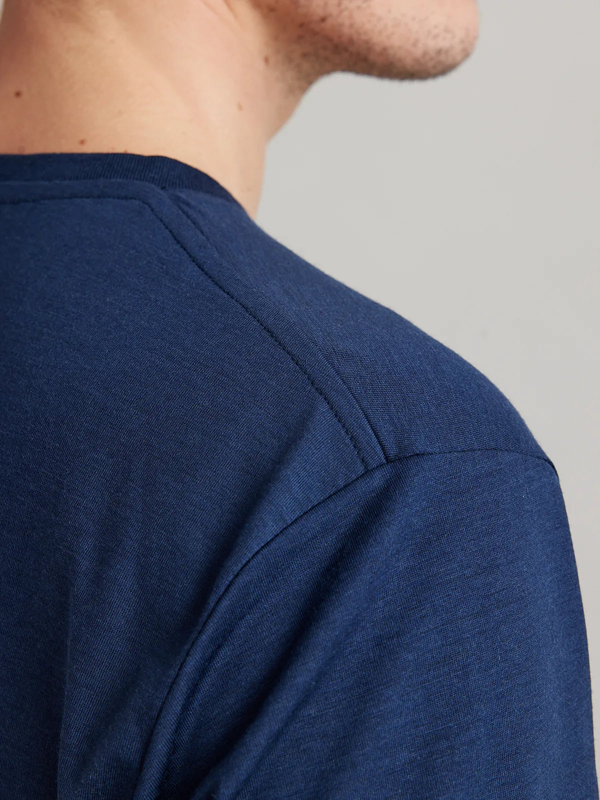 Shoulder detail of a men's dark navy blue merino wool T-shirt from Wolk, emphasizing fine stitching and quality.