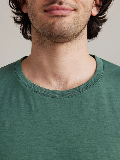 Close-up view of the collar of a pine green men's merino wool T-shirt by Wolk, showcasing European craftsmanship.