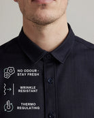 Close-up of a man wearing a dark navy button-up merino wool denim shirt with, showing the classic collar and corozo buttons. White text overlays list product benefits: 'NO ODOUR - STAY FRESH', 'WRINKLE RESISTANT', and 'THERMO REGULATING'.