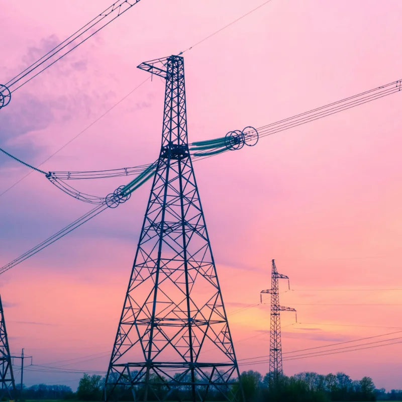 Power transmission tower against a pink and purple sunset sky