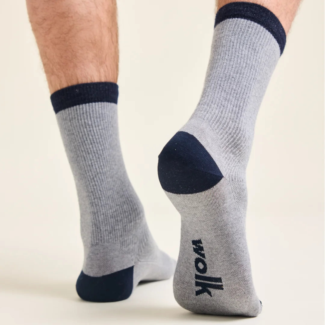 Gray merino wool socks with navy accents and Wolk logo worn by a person on a beige background