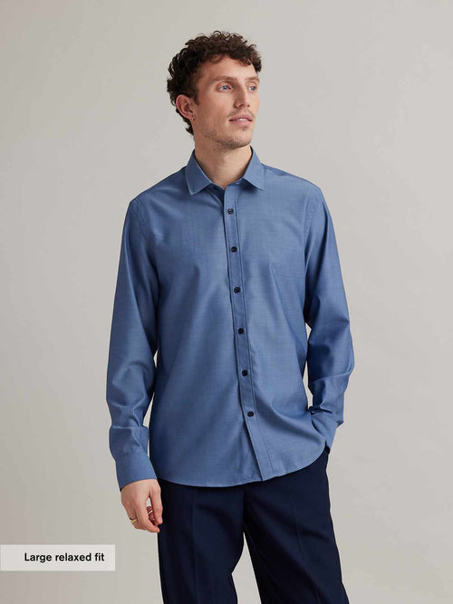 Man wears a mid navy twill colored merino wool shirt from Wolk with long sleeves and classic collar in relaxed fit