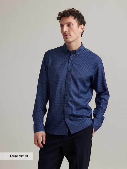 man wearing merino shirt on bike in blue color with small graph check and button down collar in slim fit