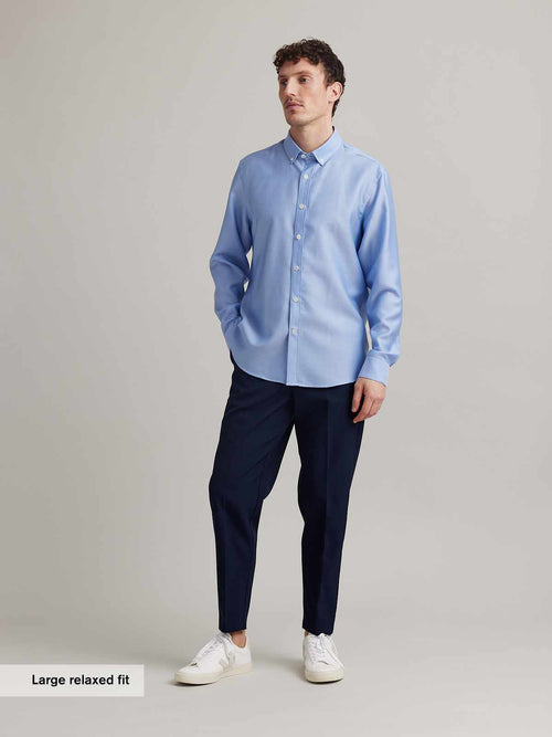 Man wears light blue oxford button-down collar shirt with white corozo buttons in relaxed fit