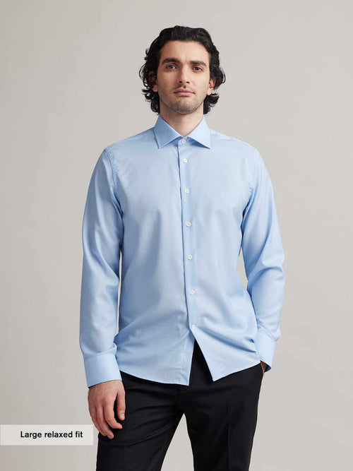 Man wears a light blue formal merino wool shirt with white buttons and spread collar in relaxed fit