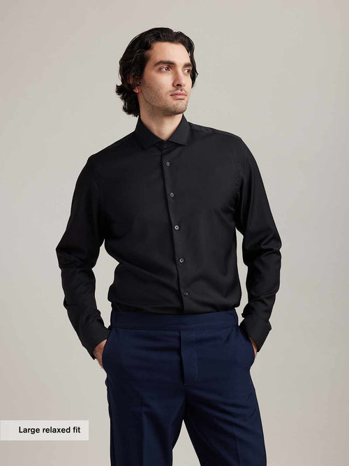 Man wears black merino wool formal shirt with spread collar and long sleeves in relaxed fit