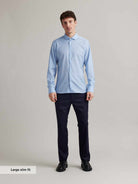 Man wears a light blue merino wool shirt with spread collar and white buttons in slim fit from Wolk
