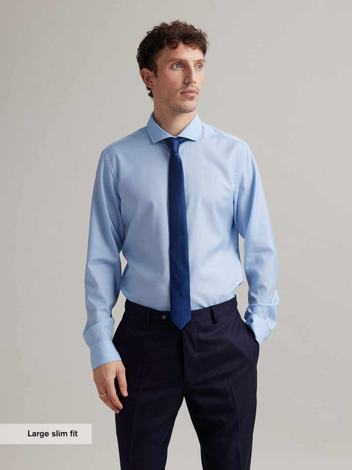 Man wears long sleeve woven shirt in merino wool light blue color and spread collar with tie