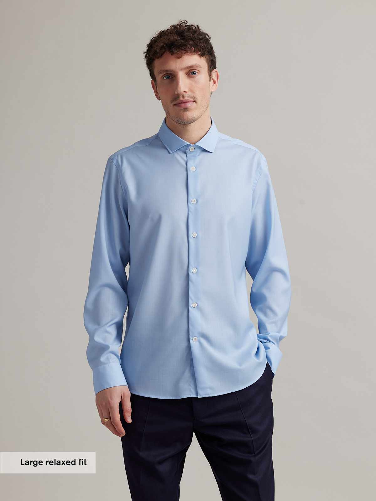 Man wears a light blue merino wool shirt with spread collar and white buttons in relaxed fit from Wolk