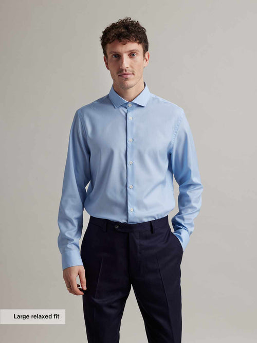 Man wears a light blue merino wool shirt with spread collar and white buttons in relaxed fit from Wolk
