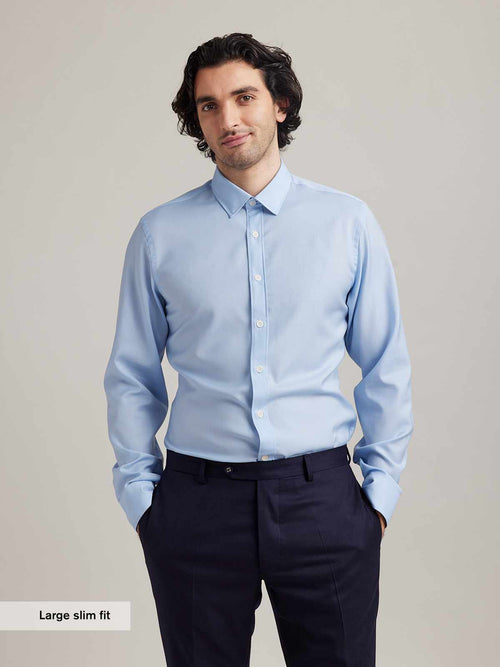 Man wears a light blue merino wool shirt from Wolk with classic collar white buttons and long sleeves