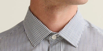Close-up of a person wearing a striped shirt with a neutral background