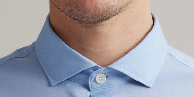 Close up of person wearing a light blue merino wool shirt with spread collar