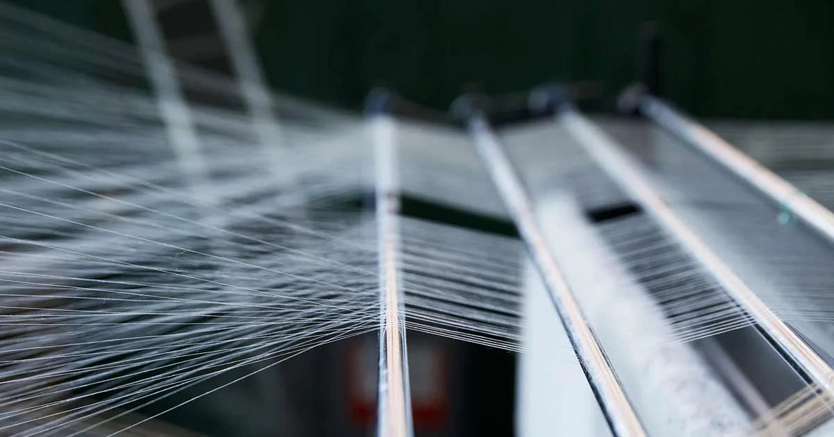 Close-up of a loom with threads and metal components.