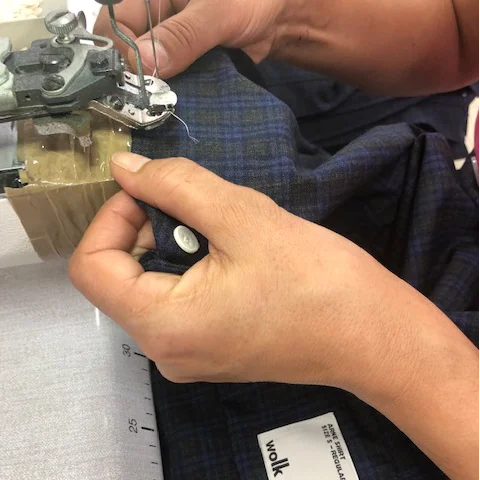 Person sewing fabric with a sewing machine, close-up of hands and machine.