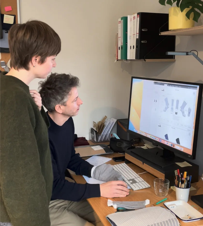 Wolk office people working together at a desk with a computer monitor displaying a software interface.