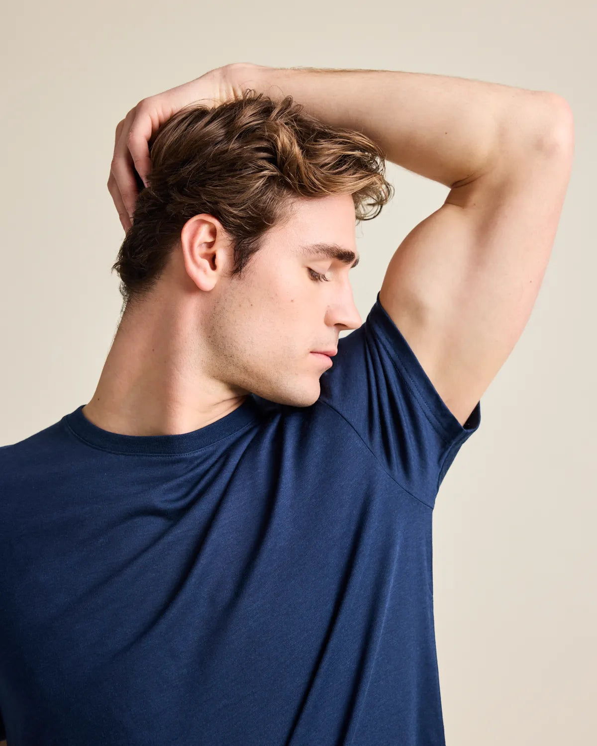 man wearing a navy merino tshirt and smelling the armpit to check the freshness