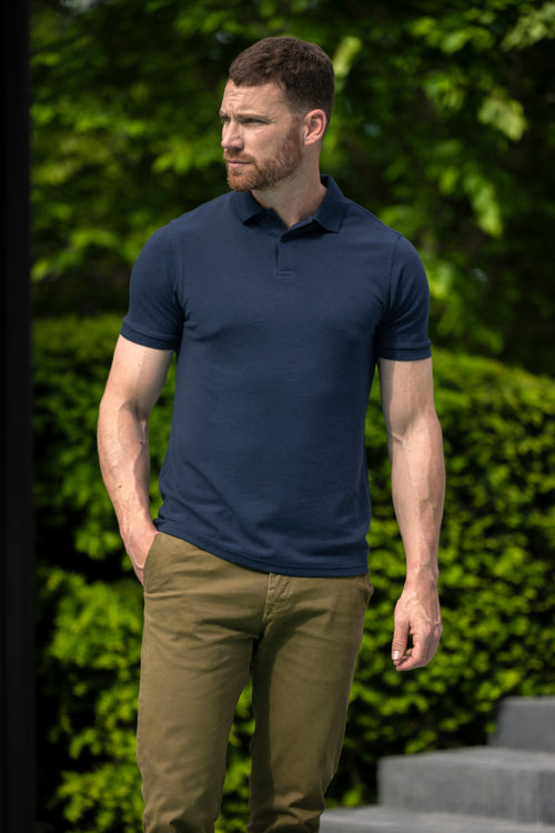 Man wearing short sleeve merino wool polo with rib cuff and collar in navy blue