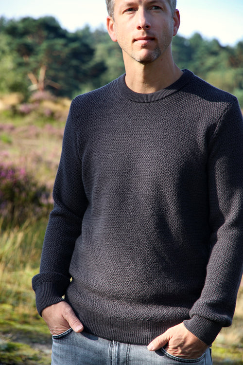 Man wearing a merino wool sweater in anthracite dark grey in rice knit stitch
