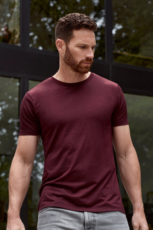 Man wearing merino T-shirt in burgundy red color with short sleeves and round neck